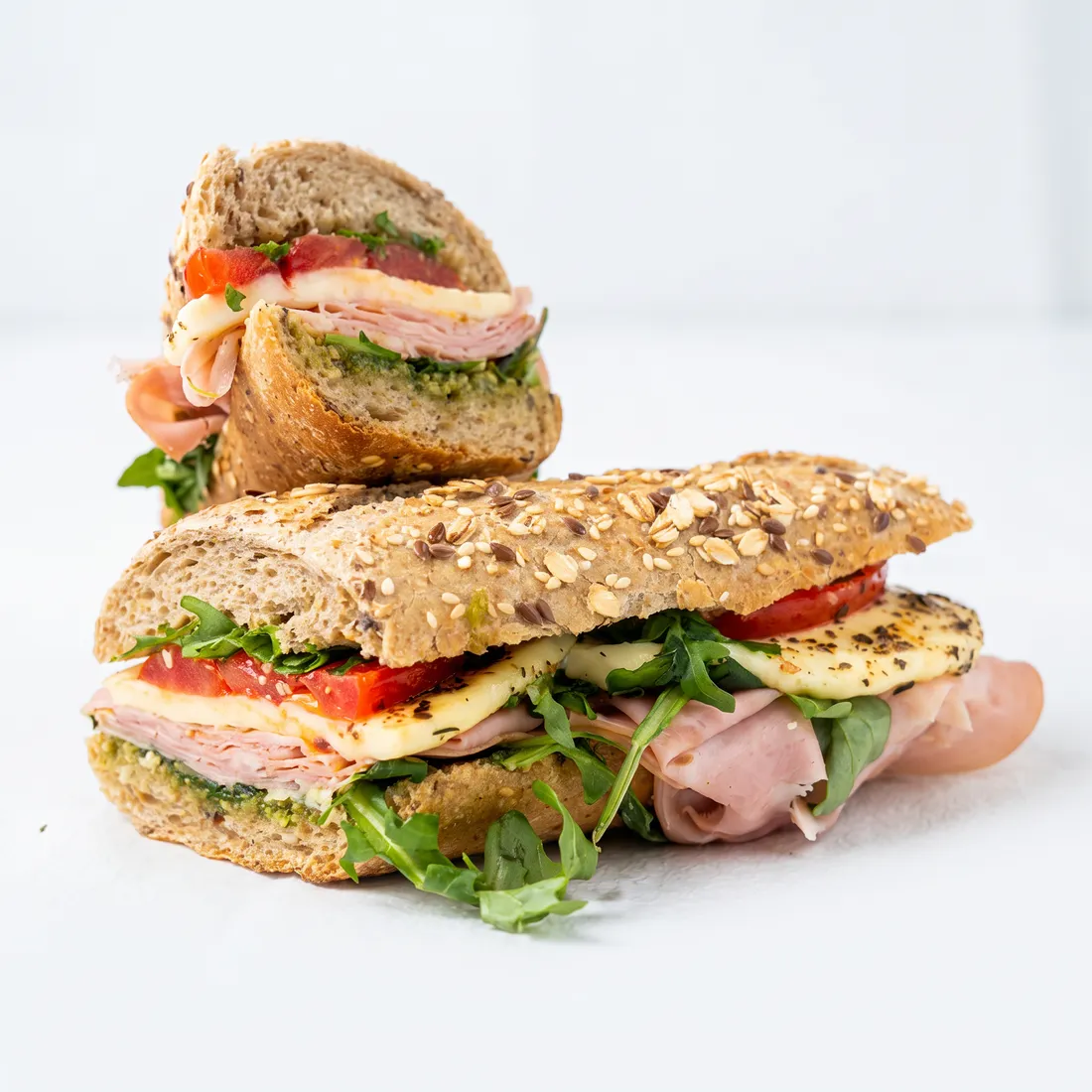 Sandwich maison sur baguette grise : jambon, fromage grillé, tomate, roquette et pesto